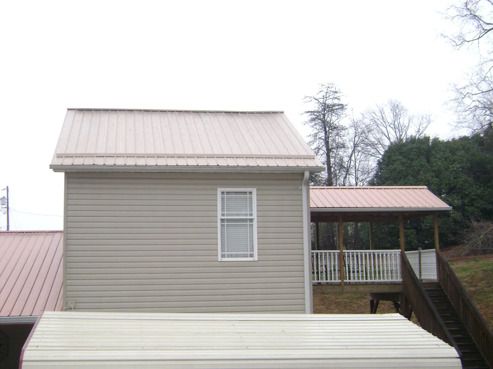 Tan metal roofs on a two story addition and attached porch, from a Roof Replacement job in Morristown